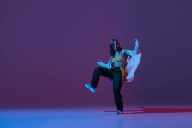 Esnek genç kız, dansçı hip-hop dansçısı ya da neonlu koyu mor arka planda izole edilmiş deneysel dans. Çağdaş dans. Müzik, gençlik yaşam tarzı, moda, tarz. İlan için alanı kopyala