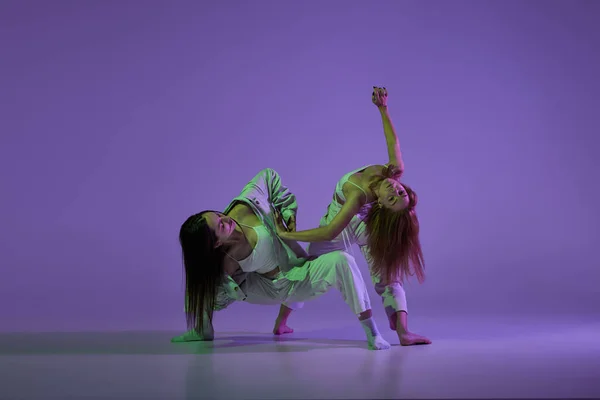 実験舞踊 2人の若い女の子が動き アクションは紫色の背景に隔離された 新しいダンススタイル 若者文化 音楽やファッション トレンドの概念 柔軟で優雅なダンサー — ストック写真