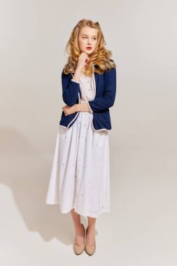 Rüya görüyordum. Gri arka planda izole edilmiş, eski moda kıyafetler giyen, şık, genç, sarışın bir kadın. Güzellik, reklam, duygular, yüz ifadesi konsepti.