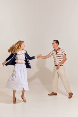 Heyecanlı, genç, güzel, şık, modaya uygun giyinmiş, arka planda yalnız dans eden bir çift. 60 'lar, 70' ler Amerikan kültürü konsepti. Retro moda, ilişki, aşk, duygular ve reklam.