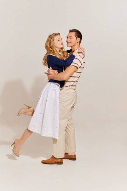 Klasik moda elbiseli mutlu aile çifti hafif arka planda soyutlanmış bir şekilde sarılıyorlar. 60 'lar, 70' ler Amerikan kültürü konsepti. Retro moda, ilişki, aşk, duygular ve reklam.