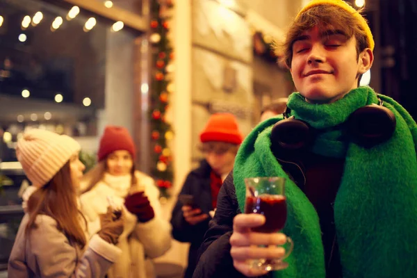 Emotional young people, friends meeting, smiling, drinking hot drinks at evening city street at winter time. Emotions, love, friendships, ad, sales concept. Winter fashion collection