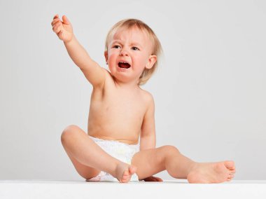 Ağlayan bebek. Gri stüdyo arka planında izole edilmiş bebek bezi giymiş küçük tatlı bir kız. Aile kavramı, çocukluk, annelik, hayat, doğum. İlan için alanı kopyala