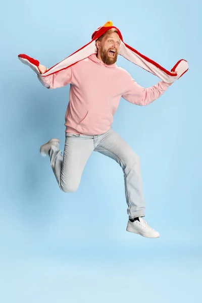 Wow, football fans emotions. Happy bearded man in casual style clothes jumping over blue background. Concept of vivid emotions, happiness, active life position. Copy space for ad