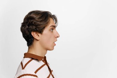 Beyaz arka planda izole edilmiş yakışıklı bir gencin profil görüntüsü. Adam şaşırmış görünüyordu. İnsan duyguları, yüz ifadeleri. Reklam için kopyalama alanı olan pankart