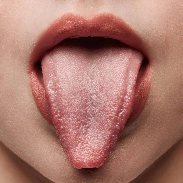 Tasting something. Closeup sexy female lips with nude color lipstick. Sensual womens open mouth with sticking out tongue. Beauty, fashion, style concept, Cropped image