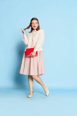 Mavi arka planda poz veren eski moda elbiseli komik güzel bir kızın portresi. Eski moda, iş, eğitim ve olumlu duygular kavramı. İlan için alanı kopyala