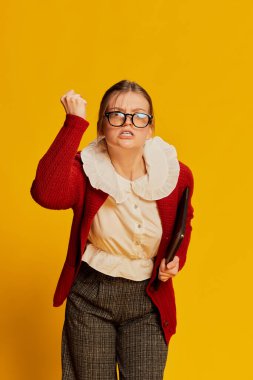 Sarı arka planda poz veren eski moda kıyafetler giyen genç bir kız. Eski moda, iş, eğitim ve duygular. İlan için alanı kopyala