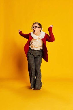 Sarı arka planda poz veren eski moda kıyafetler giyen genç bir kız. Eski moda, iş, eğitim ve duygular. İlan için alanı kopyala