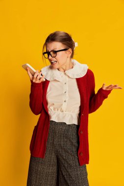 Sarı arka planda poz veren eski moda kıyafetler giyen genç bir kız. Eski moda, iş, eğitim ve duygular. İlan için alanı kopyala