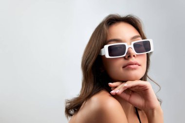 Self-confidence. Young stylish beautiful girl in fashionable eyewear isolated over grey background. Closeup. Concept of beauty, fashion, style, vogue, summer, vacation and ad