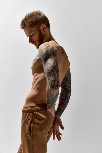 Elegance and courage. Young 30 years old man posing shirtless. Perfect muscular body shape. Tattoo body art. Concept of fashion, style, body aesthetics, beauty, mens health.