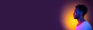 Horizontal banner with portrait of young african man over background in neon light. Beauty, fashion, youth concept. Copy space for ad, text