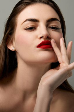 Closeup portrait of beautiful brunette model girl with long straight hair and bright red lipstick on lips. Concept of beauty, fashion, style, emotions. Model with well-kept skin and bare shoulders