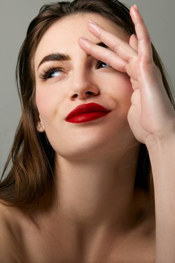 Closeup portrait of beautiful brunette model girl with long straight hair and bright red lipstick on lips. Concept of beauty, fashion, style, emotions. Model with well-kept skin and bare shoulders