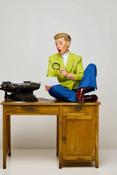 Business woman, journalist. Fashionable middle age blonde woman with short haircut in stylish clothes among retro interior objects over light background. Fashion, mental health, ad, emotions concept.