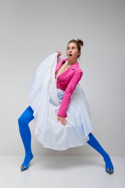 Dance. music. Young expressive woman in blue tights and white skirt in motiona and action isolated over light background. Concept of high fashion, beauty, ad. Looks stylish