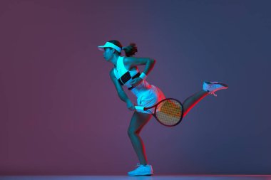 Portrait of young professional emotional tennis player in sports uniform in motion, action over gradient pink-purple background in neon light. Sport, fashion, energy, motivation concept