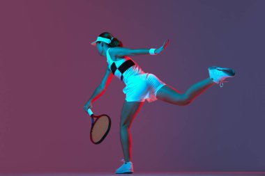 Back view of professional tennis player playing tennis over pink-purple background in neon light. Concept of sport, health, strength, action, motion, lifestyle. Copy space for ad