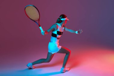 Back view of professional tennis player playing tennis over pink-purple background in neon light. Concept of sport, health, strength, action, motion, lifestyle. Copy space for ad