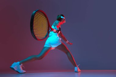 Back view of professional tennis player playing tennis over pink-purple background in neon light. Concept of sport, health, strength, action, motion, lifestyle. Copy space for ad