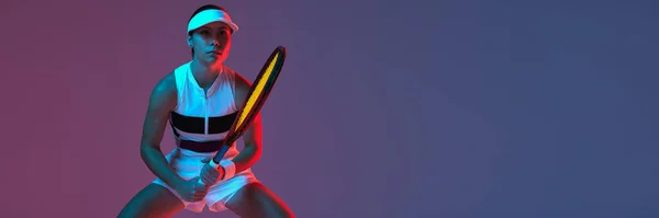 Portrait of young professional emotional tennis player in sports uniform in motion, action over gradient pink-purple background in neon light. Sport, fashion, energy, motivation concept. Banner