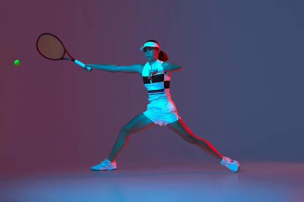 Portrait of young professional emotional tennis player in sports uniform in motion, action over gradient pink-purple background in neon light. Sport, fashion, energy, motivation concept