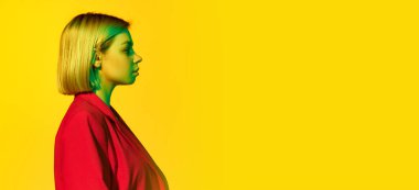 Sarı saçlı, kırmızı ceketli, sarı arka planda poz veren genç bir kız profili. Reklam ve metin için kopyalama alanı olan pankart. Model sakin ve sakin görünüyor.