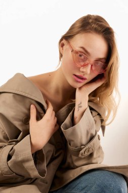 Half-length portrait of young stylish 25s age girl with bare shoulders wearing coat posing isolated over white background. Concept of fashion, trends, beauty, style, youth, ad. Looks adorable