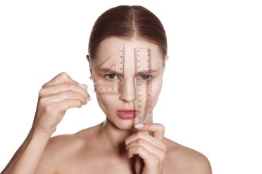 Making beauty, modifying face to make non-surgical or surgical correction, plastic surgery. correction of asymmetry. Young woman, female patient isolated on white studio background. Concept of lifting