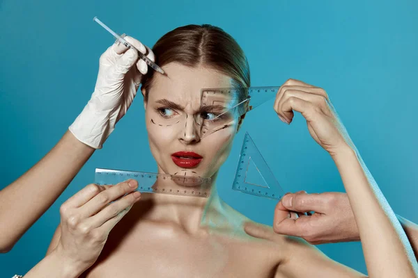 Plastic surgery or face lifting for young woman. Doctors hands wearing gloves drawing lines, holding head of female patient. Making beauty, modifying face to make surgical or non-surgical correction
