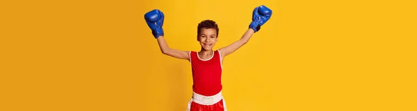 スポーティな男の子 スポーツの制服やボクシンググローブの初心者のボクサーと水平バナーは黄色の背景に手を上げます スポーツ アクティブライフスタイル 子供の感情の概念 — ストック写真