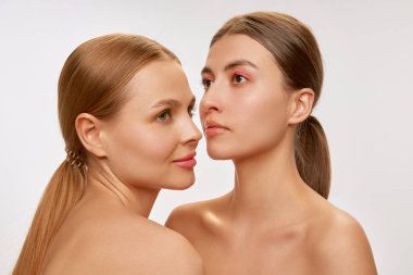 Diversity. Couple of beautiful elegant young women, blond and brunette with well-kept skin posing over light background. Concept of natural beauty, fashion, skin care and health, ad
