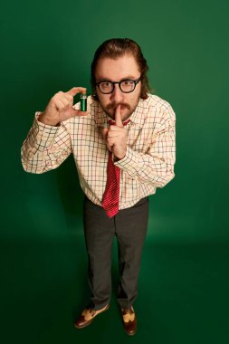 Chemist. Portrait of retro mature man with moustache and beard in eyeglasses posing in vintage fashion clothes over dark green background. Concept of retro style, emotions, business, work