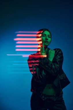 Fantezi. Genç ve şık bir kadının yarım boy portresi koyu mavi arka planda, neon ışıklı çizgilerle poz veriyor. Çağdaş sanat, moda, siber punk, fütürizm kavramı