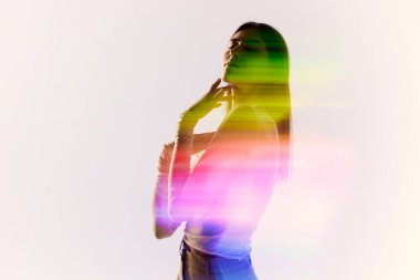 Şefkat. Beyaz arka planda poz veren sevimli bir genç kadının silüet portresi. Vücudunda karışık neon renkli bir ışık var. Çağdaş sanat, moda, gelecekçilik kavramı