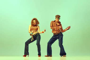 Feeling rhythm. Couple happy people, man and woman in retro style clothes dancing disco dance over green background. Concept of 1970s, 1980s fashion, music, hippie lifestyle clipart