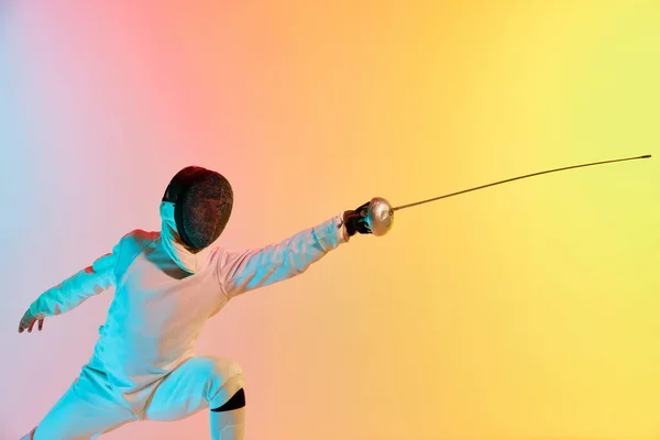 若い男 ネオンの光のグラデーションピンク黄色の背景にフェンシングの剣の練習を持つ男性のフェンシング スポーツマンはフェンシング技術を示しています 広告のコピースペース — ストック写真