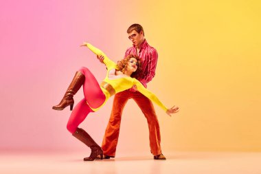 Emotions in movemets. Young stylish emotional man and woman, professional dancers in retro style clothes dancing disco dance over pink-yellow background. 1970s, 1980s fashion, music concept clipart