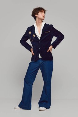 Gri arka planda izole bir şekilde poz veren şık, yüksek moda bir çocuğun moda portresi. Erkeklik ve kadınlık. Modern moda kavramı, eşsizlik, reklam