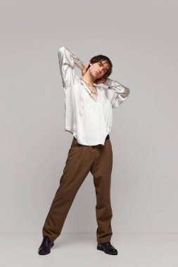 Sakinlik ve kendine güven. Gri arka planda soyutlanmış bir şekilde poz veren şık, yüksek moda bir çocuğun portresi. Erkeklik ve kadınlık. Modern moda kavramı, eşsizlik, reklam