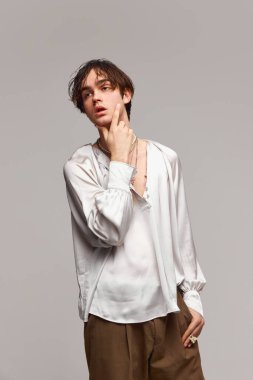 Tarz. Gri arka planda izole bir şekilde poz veren şık, yüksek moda bir çocuğun moda portresi. Erkeklik ve kadınlık. Modern moda kavramı, eşsizlik, reklam