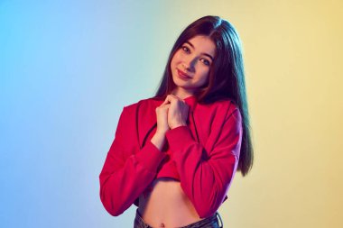 Hayal gücü. Uzun saçlı çekici bir kızın yarım boy portreleri pembe sarı arka plandaki neon ışıkta kameraya bakıyor. İnsan duyguları kavramı, moda, güzellik, reklam