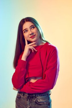 Rüyalar, düşünceler. Elleri katlanmış, kolları çenesine değen güzel bir kız. Pembe, sarı arka planda, neon ışıklı bir yere bakıyor. İnsan duyguları kavramı, moda, güzellik, reklam