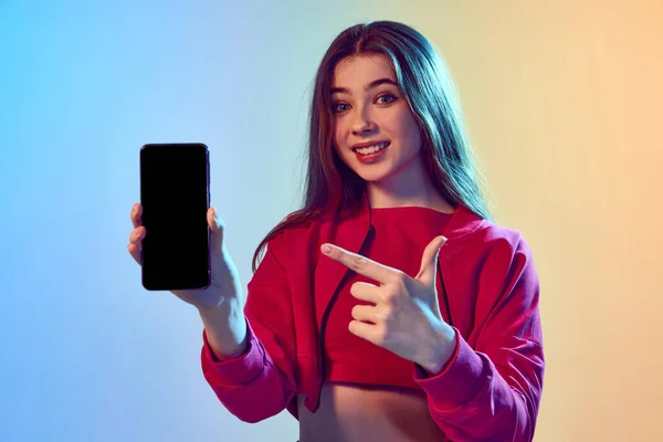 파란색 노란색 배경을 바탕으로 전화기 화면을 가리키는 소녀의 미래의 가상적 — 스톡 사진