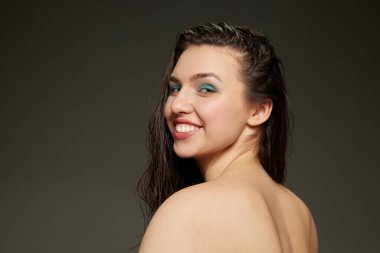 Gri arkaplanda izole edilmiş kameraya bakan genç duygusal kızın yarım boy portresi. Güzellik, moda, tarz, eğlence ve neşe konsepti. Uzun ıslak saçlı ve mavi gözlüklü bir model.