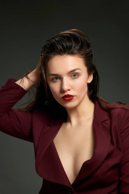 Sakin, kendine güvenen bir kız. Gri arka planda poz veren iş tarzı ceket giyen şık, duygusal bir kadın. Moda anlayışı, tarz, gençlik, güzellik