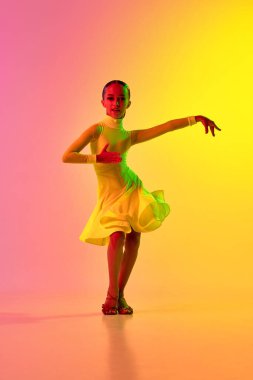 İtici güç ve enerji. Sevimli sahne kıyafetleri içinde etkileyici küçük bir kız, neon ışık filtresiyle dans eden bir balo salonunda dans ediyor. Güzellik anlayışı, profesyonel danslar.