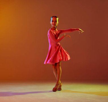 Tek kişilik performans. Stüdyo fotoğrafı, 11 yaşında bir çocuk neon ışıkta kahverengi arka planda balo dansı yapıyor. Güzellik anlayışı, profesyonel danslar.