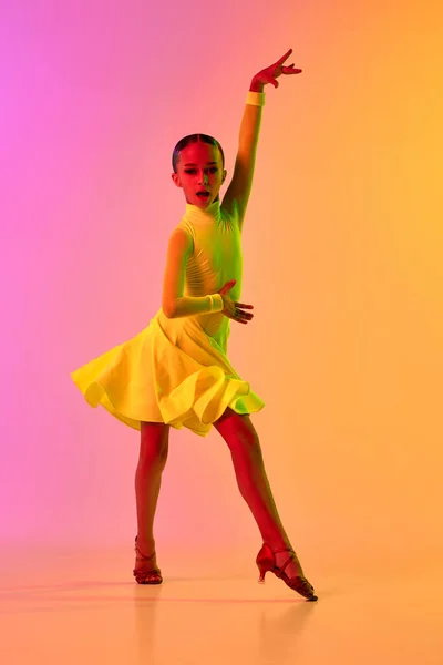 愛らしい舞台衣装を着たエレガントな女の子 ネオンライトフィルターでグラデーションピンク黄色の背景にダンスボールルームのダンスをドレスアップ 美しさ プロのダンス スキルの概念 ダンスにおける感情 — ストック写真